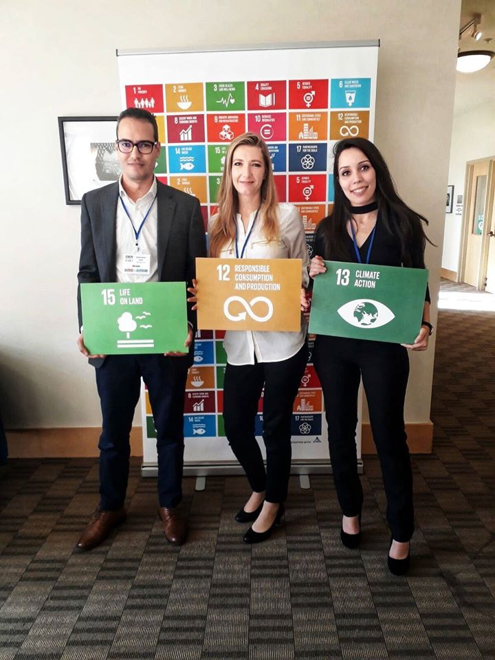 Three UC Davis Humphrey Fellows holding up cards showing the UN SDG goals