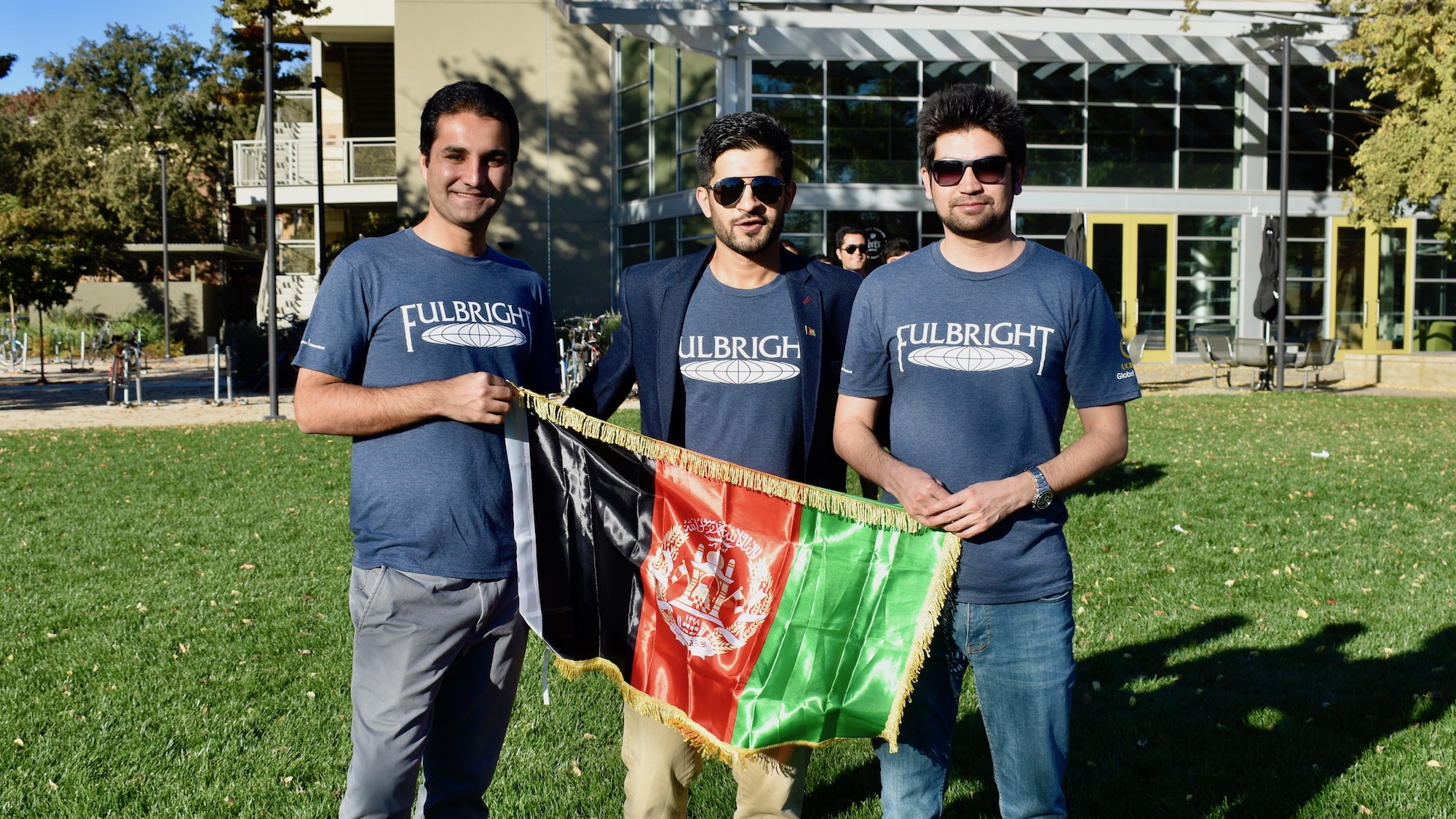 Students pose outside the UC Davis International Center with the flag of Afghanistan.