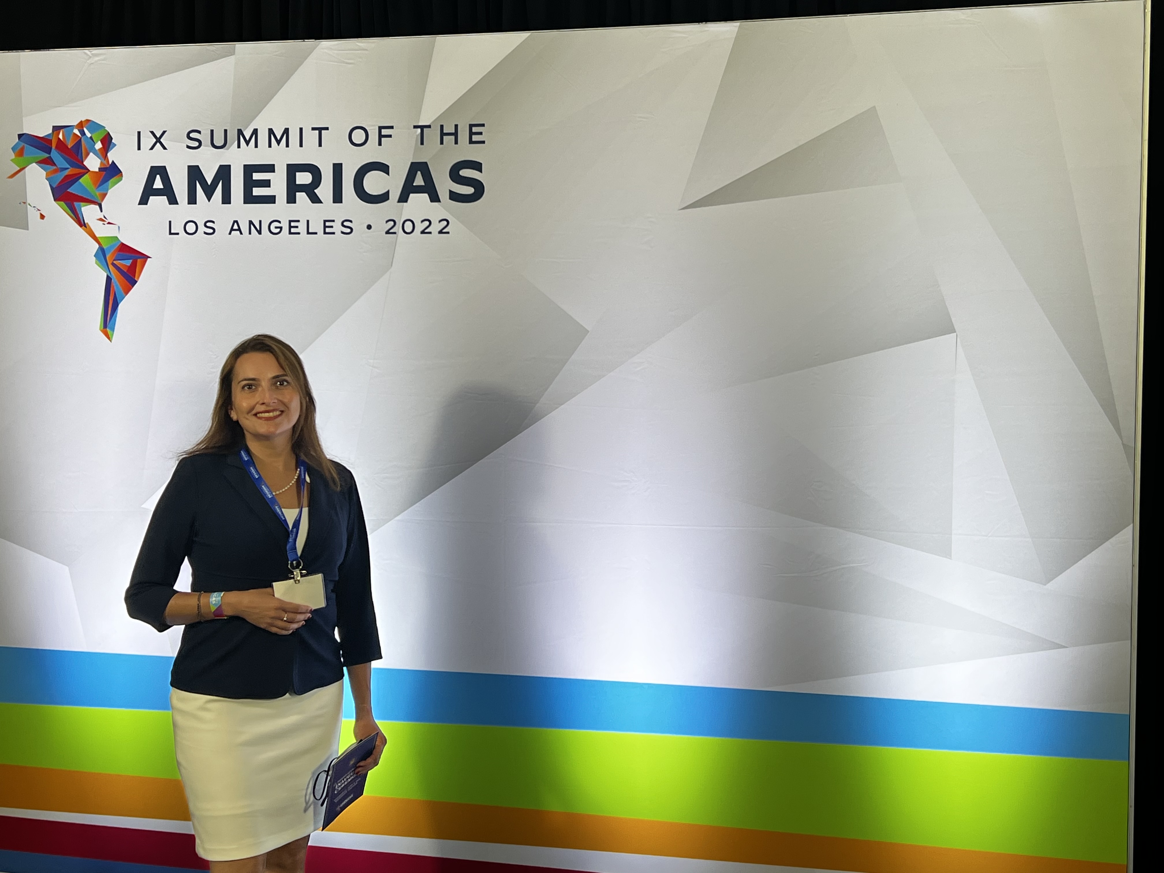 Paulina Carmona-Mora stands in front of a sign reading Summit of the Americas