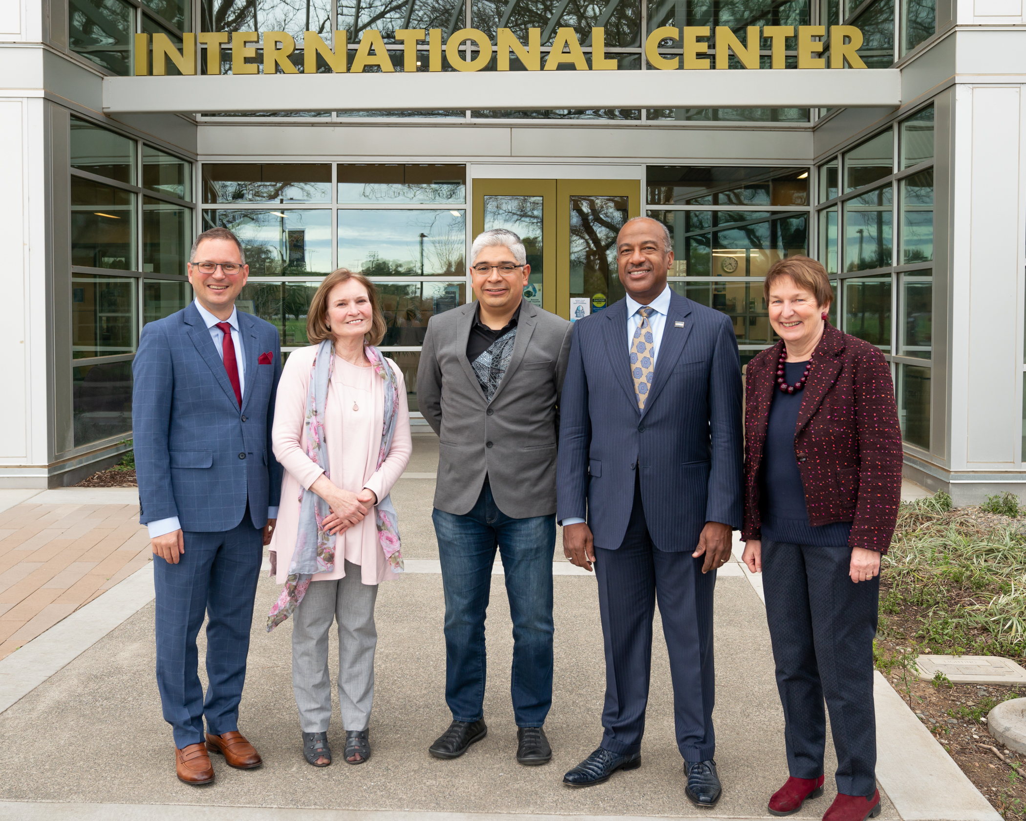 Photos of five people dressed formally standing under a sign in front of the UC International Center 