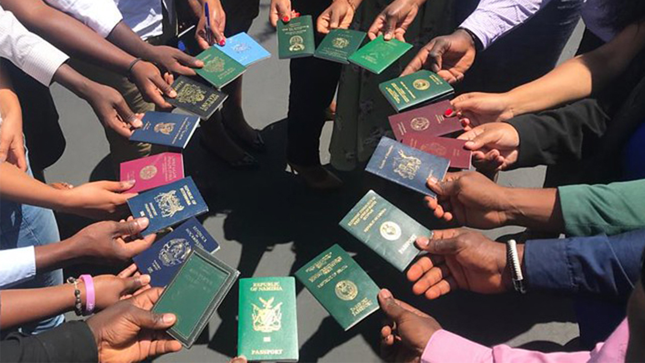 Fellows hold passports in a circle