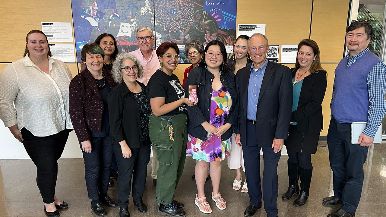 Twelve members of the Global Affairs Advisory Council stand in front of the large printed collage hanging on the wall behind them. They look toward the camera and smile in this group photo.