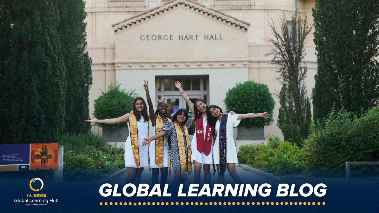 Melody Die and four female students wear dresses and graduation stoles as they celebrate in front of Hart Hall (pictured in the background) on the UC Davis campus.