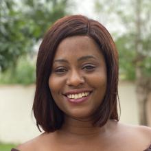 Headshot of Akosua Owusu-Efaa taken outdoors with trees behind her. Her hair is straight and styled in a shoulder-length bob.
