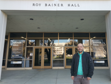 Nejib stands outside Bainer Hall in a turquoise shirt and black jacket.