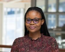 Mpho smiles in a red patterned blouse in the International Center.