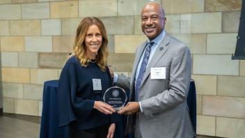 Ana Kormos and Chancellor Gary May smile at the camera while holding an award