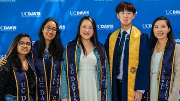 a group of students smile while wearing Global Aggies stoles.