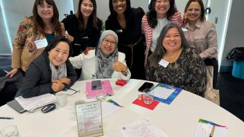 A group of women sit at a table smiling at the camera
