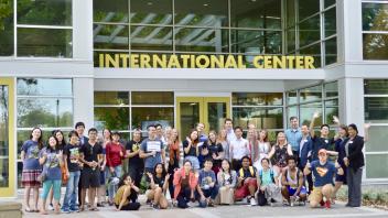 A group of UC Davis international students and Global Affairs staff smile at the camera in front of the UC Davis International Center.