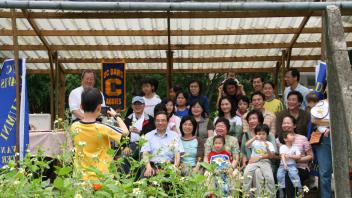 A group of UC Davis alumni in Taiwan smile at the camera while a kid takes their photo. 