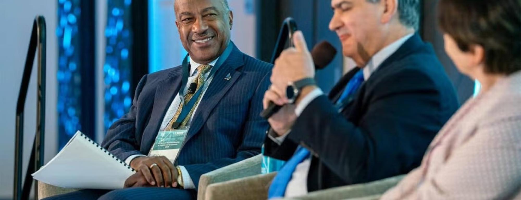 Chancellor May sits on a panel smiling.