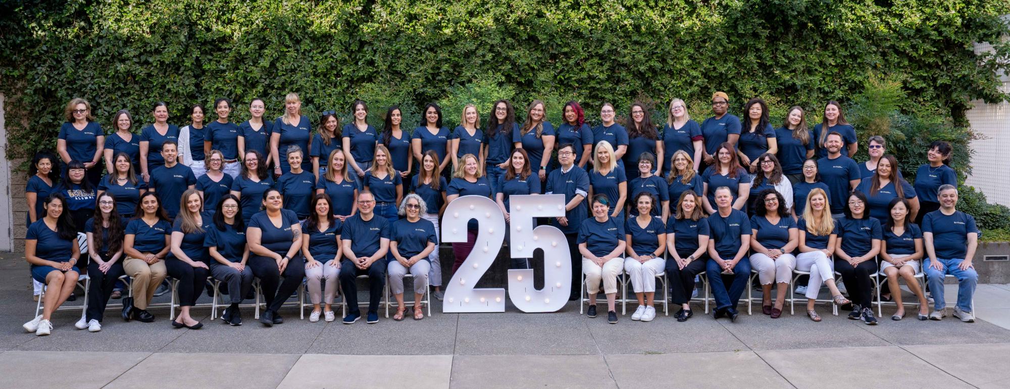 UC Davis Global Affairs staff lined up for a formal portrait with a large 25 in the center