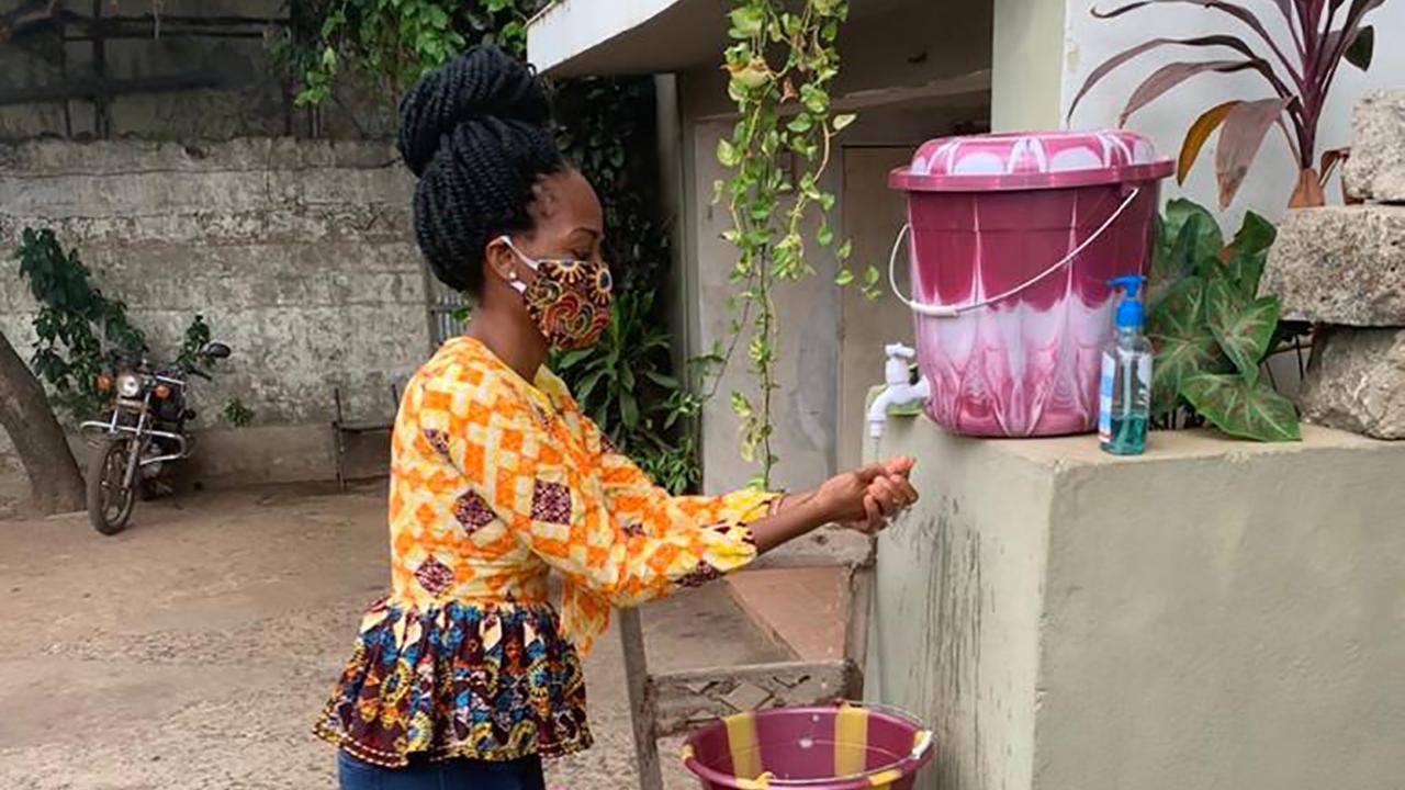 Wilsona Bumbenya Jalloh (Sierra Leone, 2018) uses a community hand-washing station set up to help prevent the spread of COVID-19 in an area previously effected by the Ebola outbreak. Wilsona Bumbenya at hand-washing station