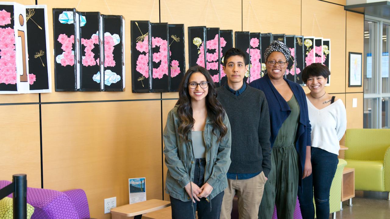 Students Bianca Medina, Marbles Jumbo Radio, Jasmine Wade and Sabrina Rose Lee stand in front of artwork at the International Center on the UC Davis campus. All created work that "re-imagined" America. Photo by TJ Ushing Global Affairs Imagining America Fellow