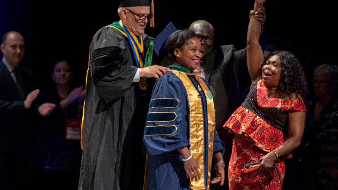 Lucy Ogbu-Nwobodo shares a triumphant moment with her mother May 18 as Dr. Frank Sousa, assistant dean at UC Davis medical school, bestows the hood designating her as a doctor of medicine. Charles Casey/UC Davis Lucy Ogbu-Nwobodo at graduation