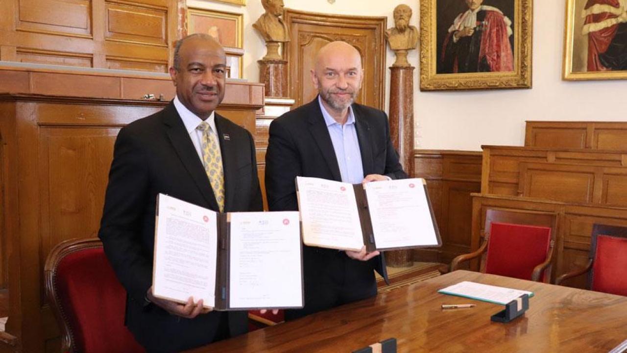In a photo from @umontpellier on Twitter May 21, Chancellor Gary S. May and Philippe Augé hold up signed documents.