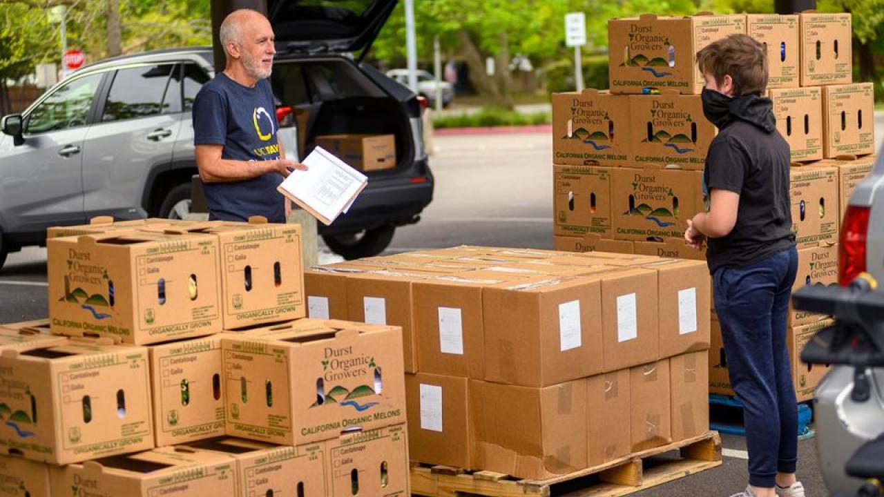 Robb Davis, left, has taken a leave of absence from Global Affairs to oversee the Yolo Food Bank’s coronavirus response. He’s coordinating food delivery, like this distribution at Davis High School.