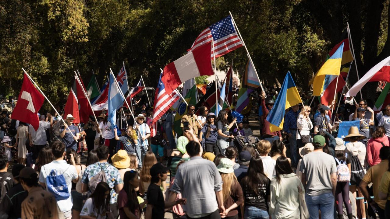 A group of people gathered outside holding up different flags from over 20 countries.