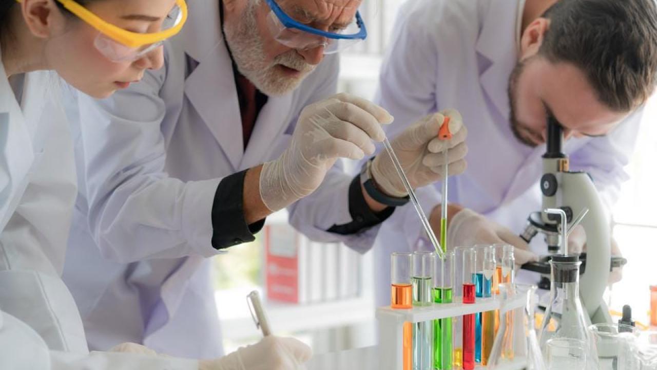 Three scientists working on an experiment in a lab