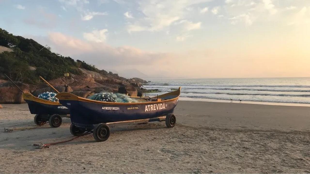 Two fishing boats sit on the sand of a Brazilian beach.