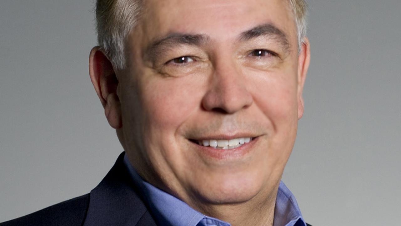 Professional Headshot of Raymond Rodriguez. He wears a black blazer and light blue collared shirt while smiling.