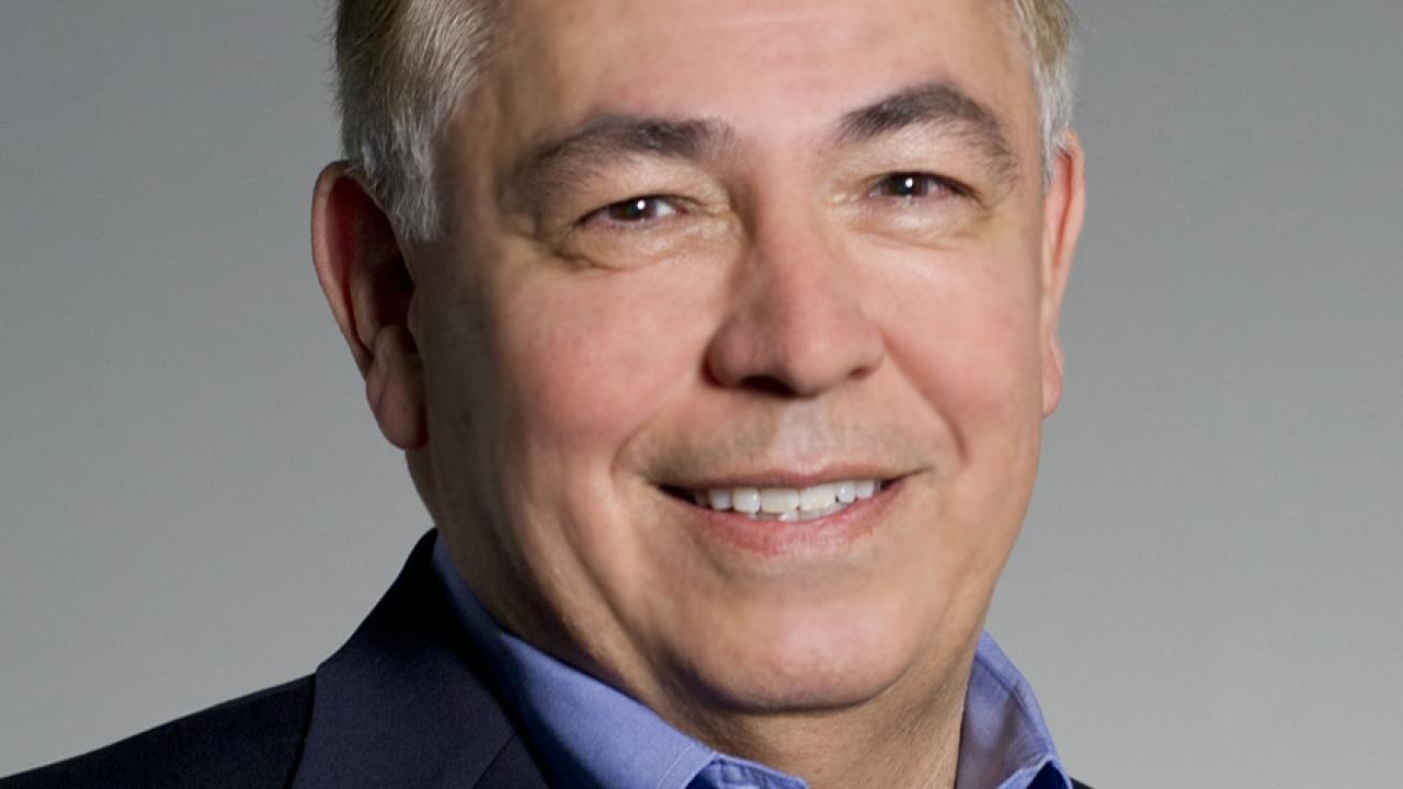 Professional Headshot of Raymond Rodriguez. He wears a black blazer and light blue collared shirt while smiling. 