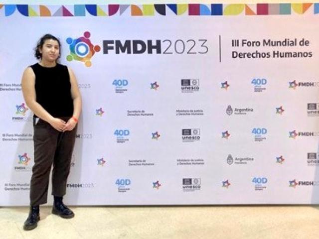 UC Davis Student Emma Tolliver poses in front of an FMDH 2023 backdrop.