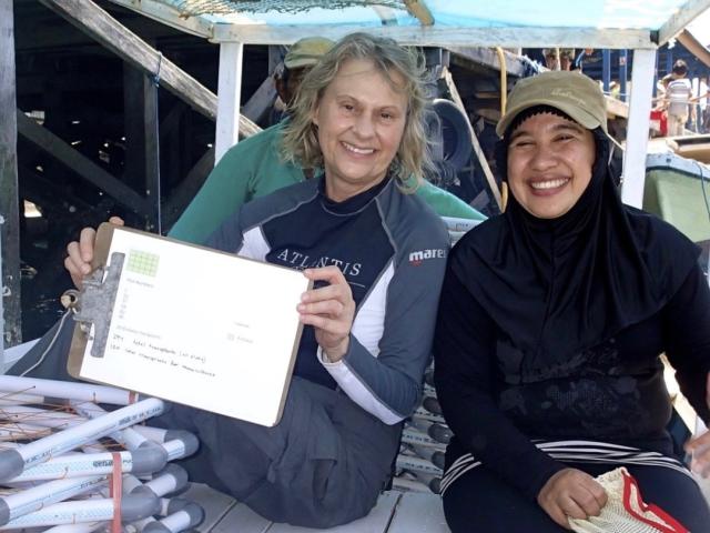 A UC Davis faculty member smiles on a boat carrying a clipboard.