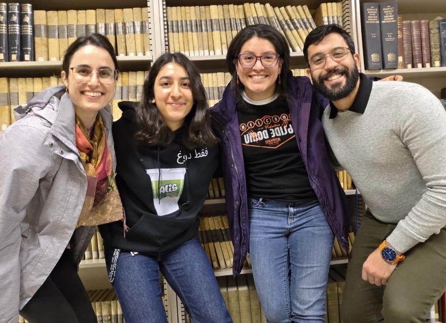 Sara,UC Davis Aggies Near and Far member Negar, Jannet, and Jeff smile for the camera in front of bookshelves
