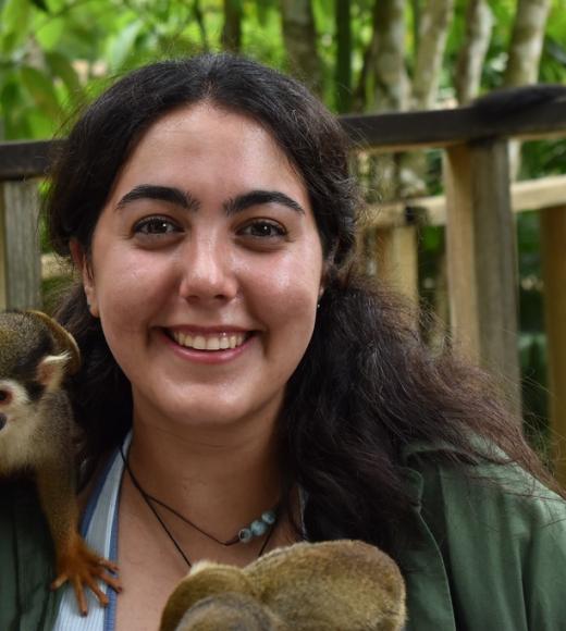 Alina smiles with a monkey on her shoulder.