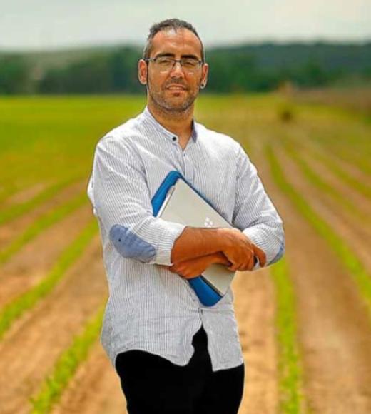 Photo of Carlos Perez Blanco posed in front of a field outside.