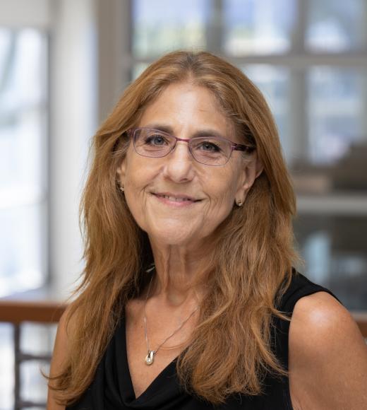 Lori smiles in a black shirt inside the International Center.