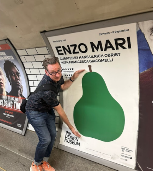 Professor Tim McNeil stands for a photo with a graphic wall art of a pear.