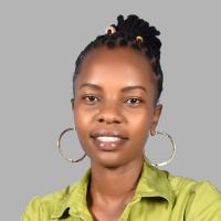 Esther Anyona smiles in a headshot with a gray background. She wears a chartreuse green collared shirt, large gold hoop earrings, and her dark hair is worn pulled back at the crown of her head and in locs with two beads--one cream colored with a circular pattern and the other red and yellow--on the top of her head.