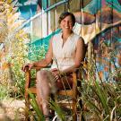 Pamela Ronald sitting on chair next to plants and art. 
