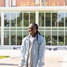 Kelsey Kalu looks at someone off to the left and smiles at them. Behind Kelsey is the Memorial Union building on the UC Davis campus, with a gold lettering that reads "Memorial Union."