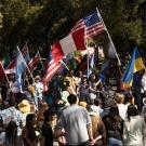 A group of people gathered outside holding up different flags from over 20 countries.