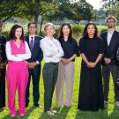 A group photo of eight Humphrey Fellows dressed in business attire stand on the grass with trees in the background.