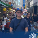 Aidan stands on a crowded street with the Global Aggies logo in the bottom right-hand corner.