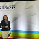 Paulina Carmona-Mora stands in front of a sign reading Summit of the Americas