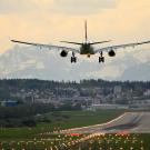 An airplane descends toward a runway at an airport in Zurich. The city and Swiss mountains unfold in the background. 