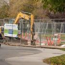A person bikes past fenced off construction on the UC Davis campus