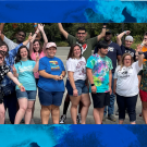 A group of Redwood Seed scholars with arms raised in a group photos and a blue watercolor backround behind them