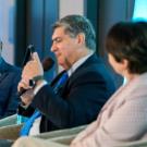 Chancellor May sits on a panel smiling.